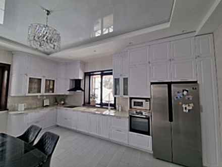 Неоклассическая кухня с белыми фрезерованными фасадами и большой системой хранения - фото - 1