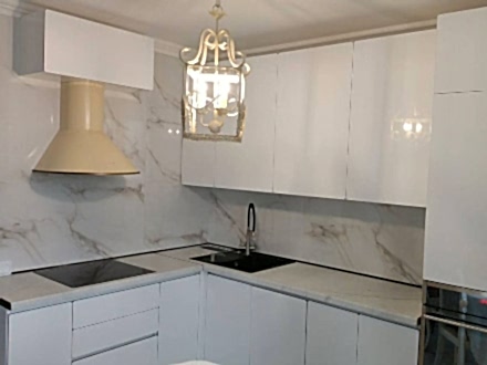 Угловая белая кухня с глянцевыми фасадами без ручек - фото - 3